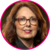 Woman with long brown hair and glasses, wearing a black top, pictured in a headshot with a blurred background and a pink circular border—an advocate for fraud prevention and strong security tactics.